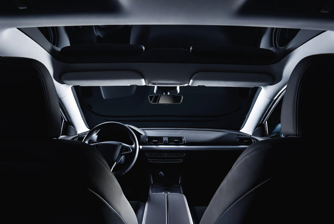 Dark car interior cabin showing headliner, dashboard and front seats