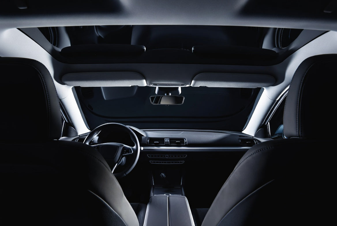 Dark car interior cabin showing headliner, dashboard and front seats