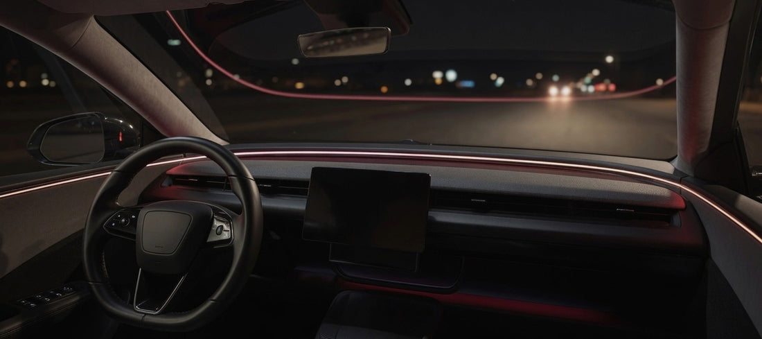 Car dashboard at night with red ambient lighting and the road ahead