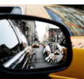 The convex blind spot mirror stuck to a wing mirror, showing traffic alongside the car