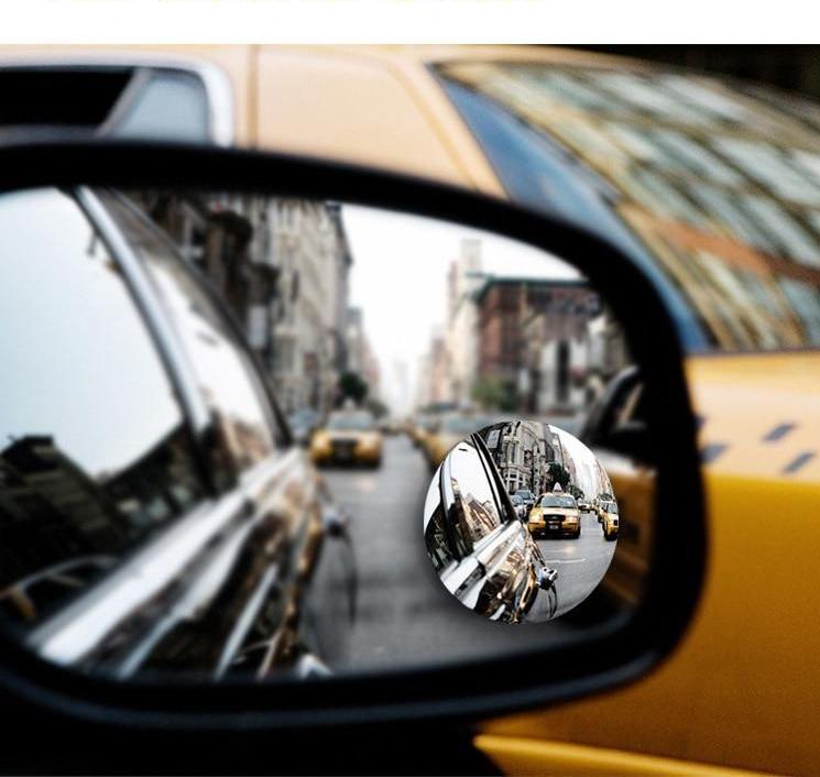The convex blind spot mirror stuck to a wing mirror, showing traffic alongside the car