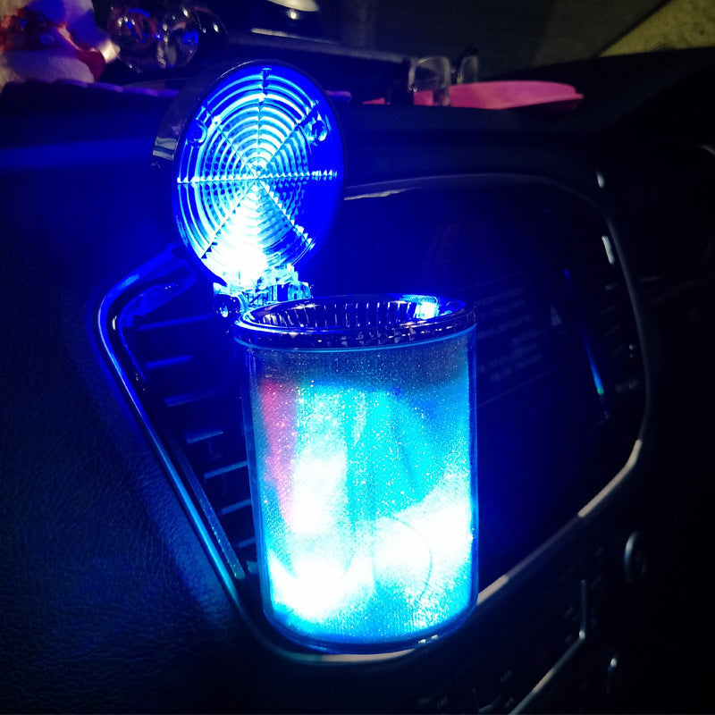 The ashtray lit blue and green in a dark car interior at night