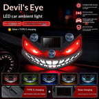Grinning devil-eye LED car window light with crimson eyes, suction-mounted on glass at night