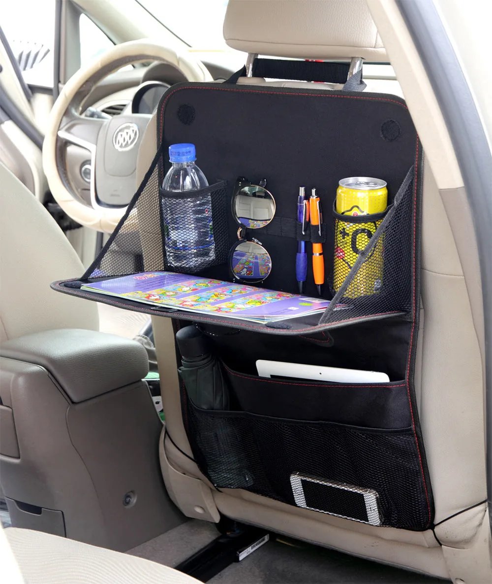 The organizer strapped to a car seat back with the tray folded down holding a bottle, tablet and pens