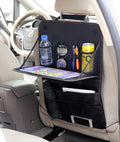 The organizer strapped to a car seat back with the tray folded down holding a bottle, tablet and pens