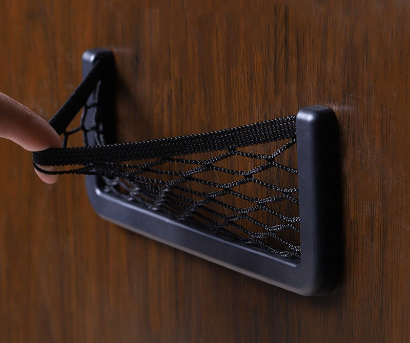 Hand pulling back the elastic mesh of a stick-on storage pocket