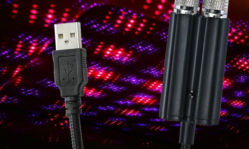 The USB star projector plugged in, with its red and violet starfield projected behind it